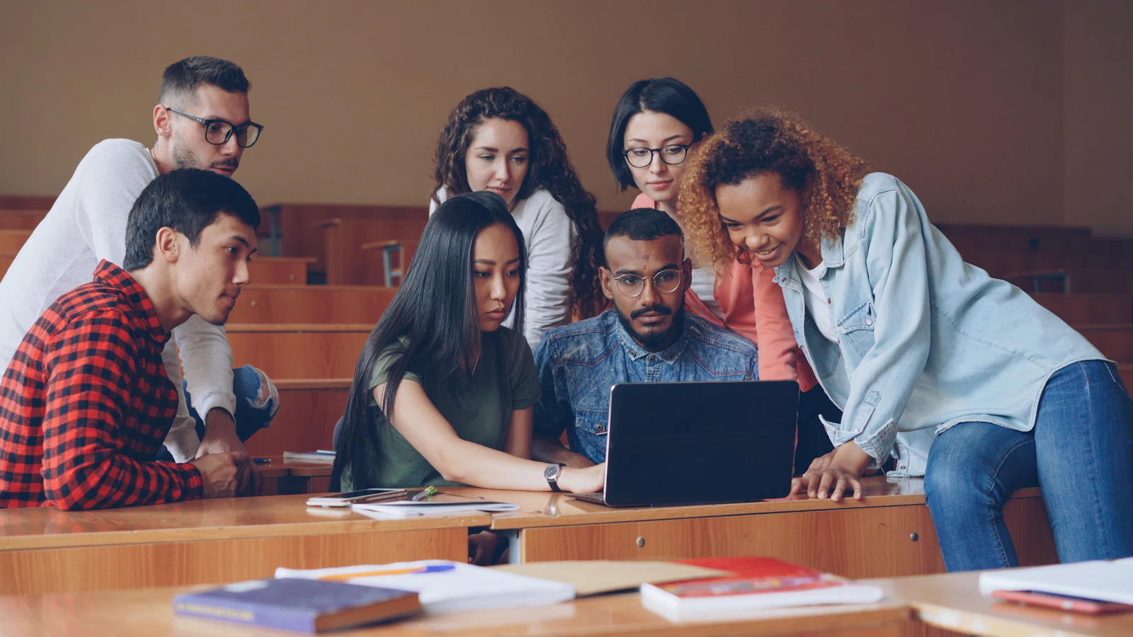 A team crowded around one laptop, working through a task together step by step.